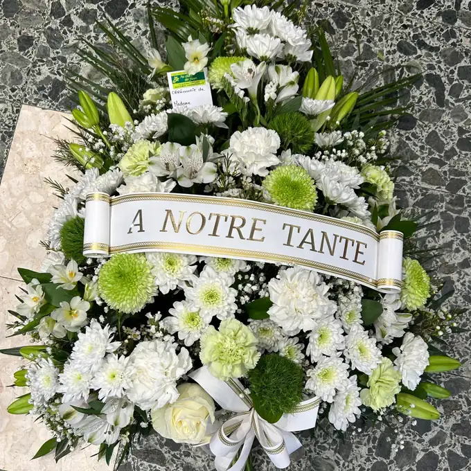 Gerbe de fleurs blanches et vertes avec un ruban « À notre tante »